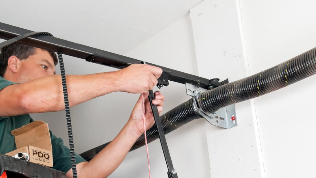 A garage door repair and service technician replacing the traveler car on a belt driven garage door opener.