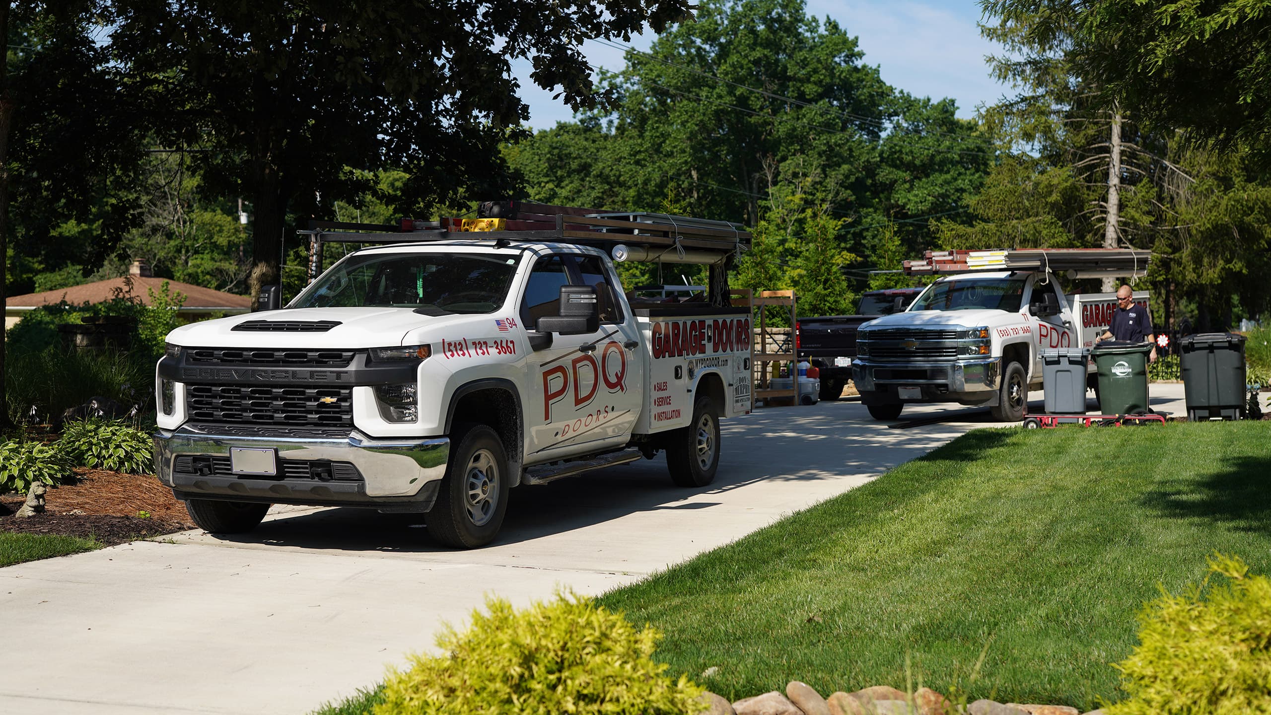 PDQ Doors service, installation, and repair trucks parked in a suburban residential driveway in the Greater Cincinnati area