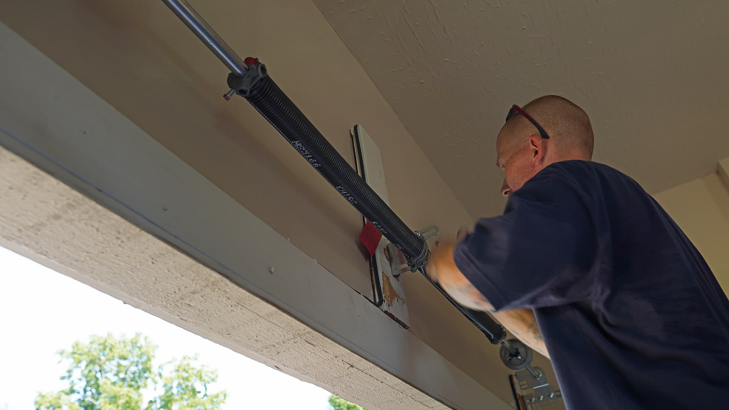 A PDQ Doors technician repairs and installs a garage door spring