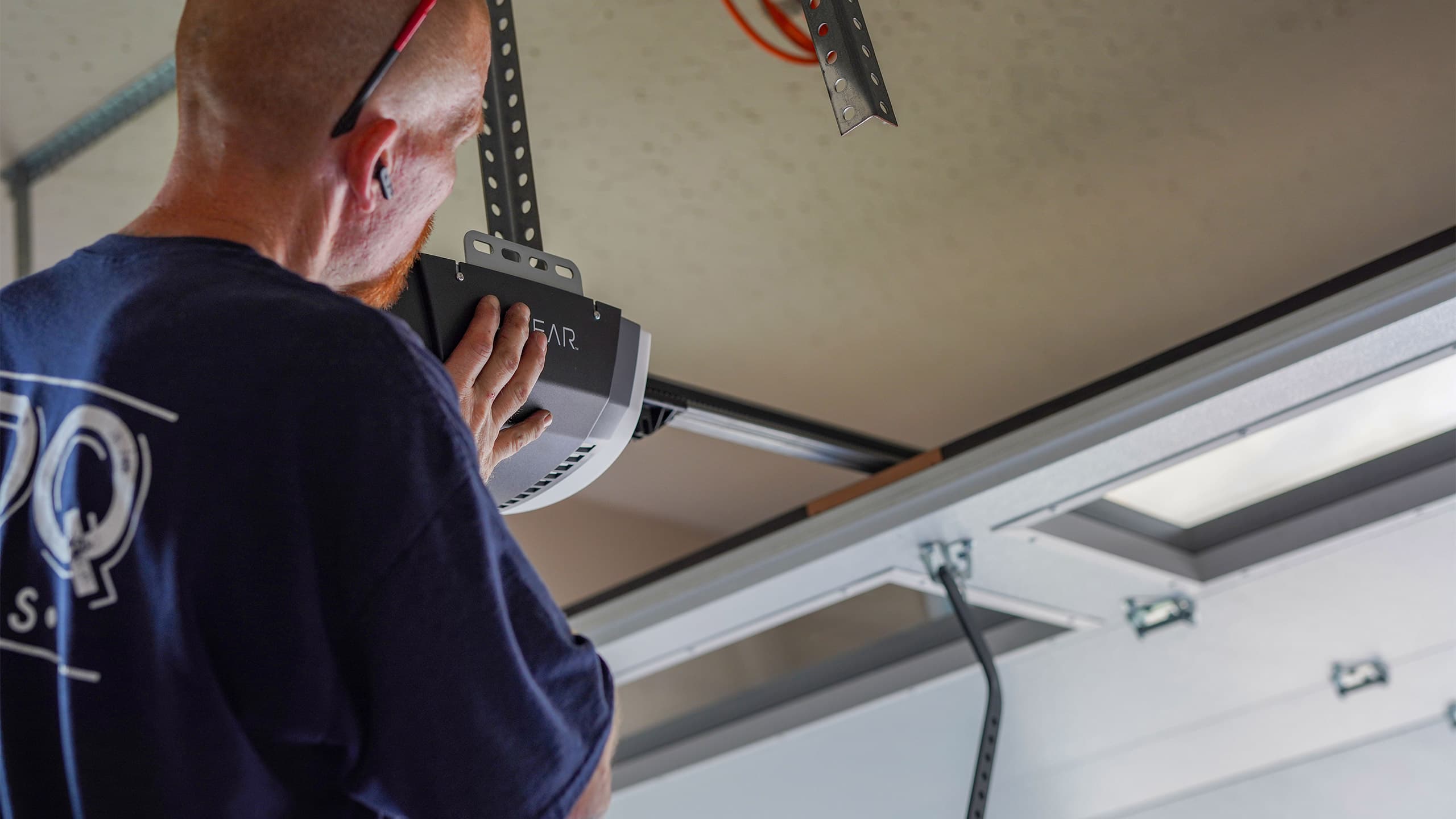 A PDQ Doors technician repairs and services a garage door opener
