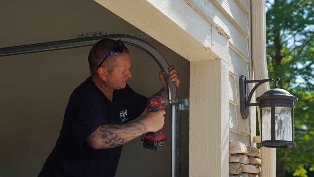 A PDQ Doors technician services and adjusts the alignment of a garage door track