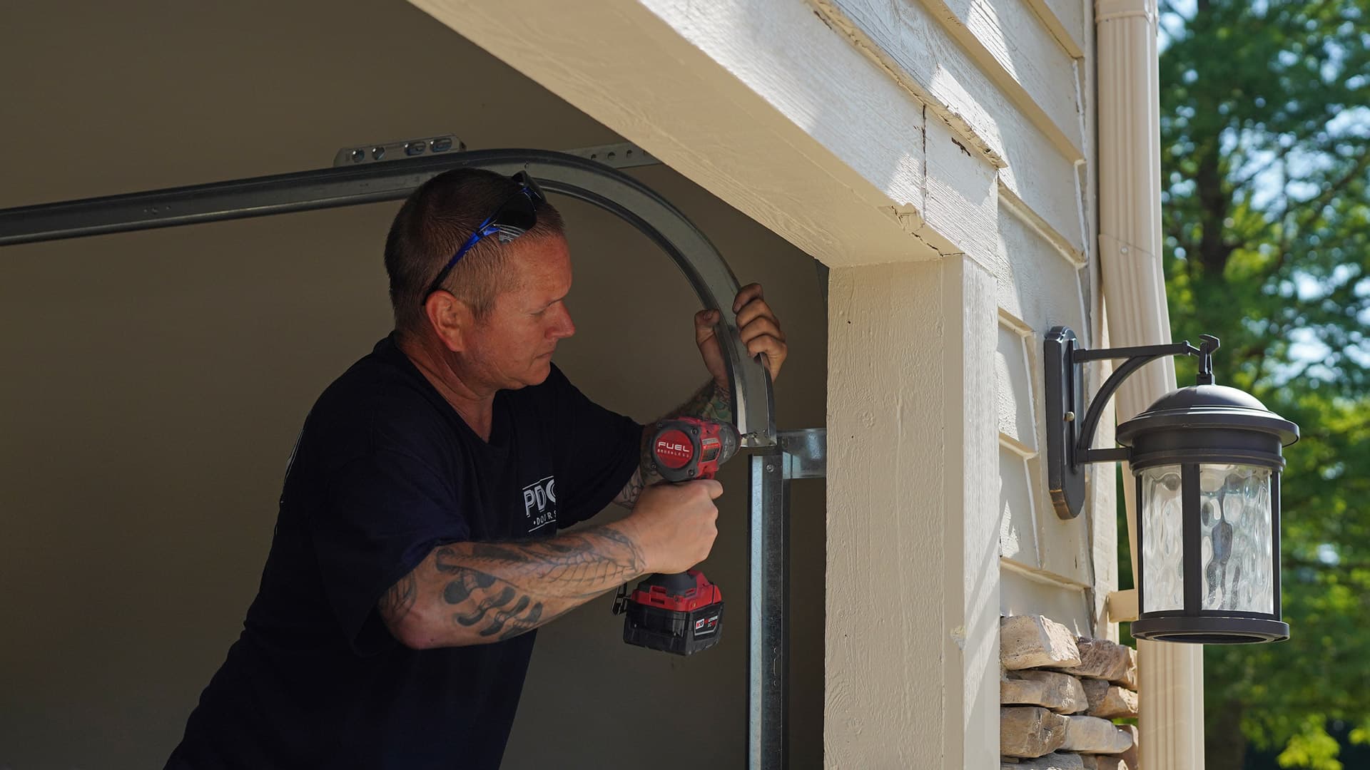A PDQ Doors technician services and adjusts the alignment of a garage door track