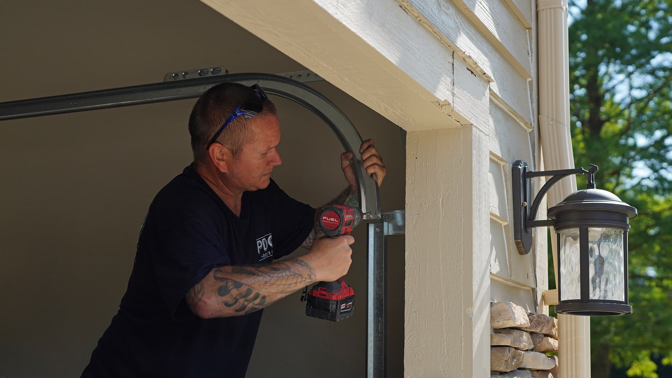 A PDQ Doors technician services and adjusts the alignment of a garage door track