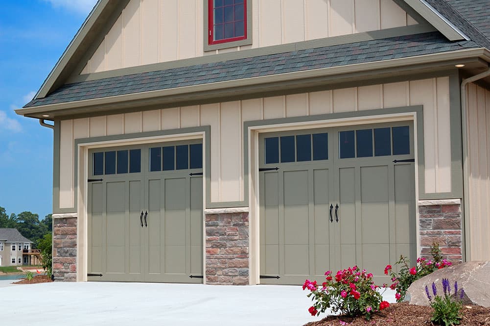 A home with a stamped steel carriage house garage door in green with Cascade windows from PDQ Doors