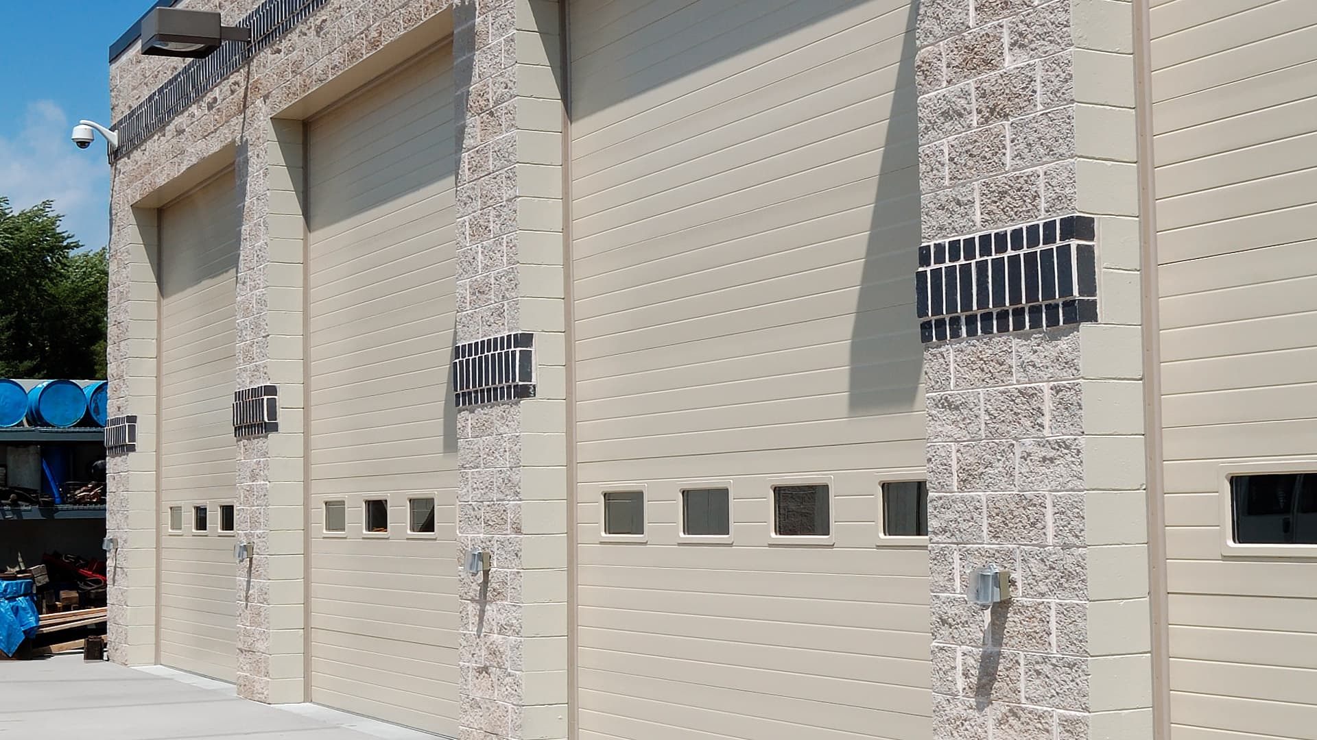 Front of a commercial building with three tan colored commercial polystyrene sandwich garage doors