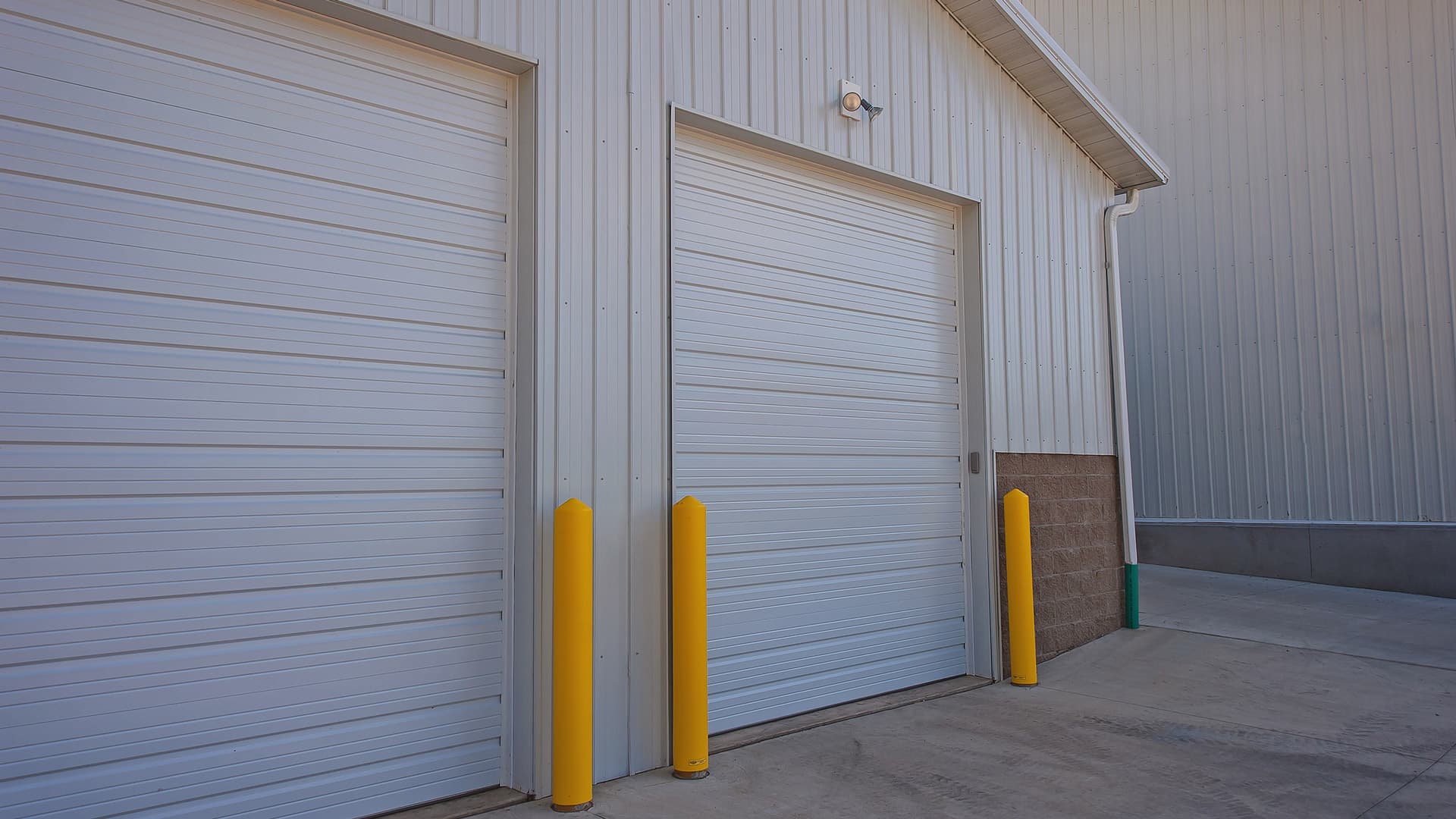Front of a commercial building with two white commercial ribbed steel garage doors