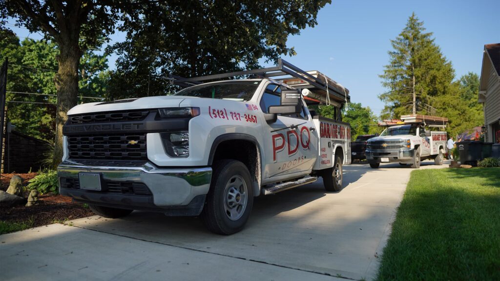 Two PDQ Doors garage door installation, service, and repair trucks parked in a driveway