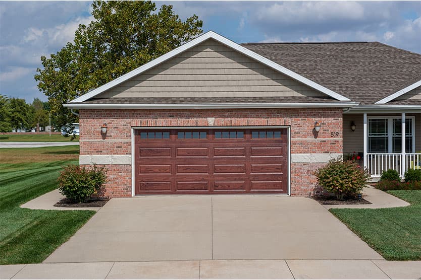 A suburban home with a traditionall garage door in brown with windows