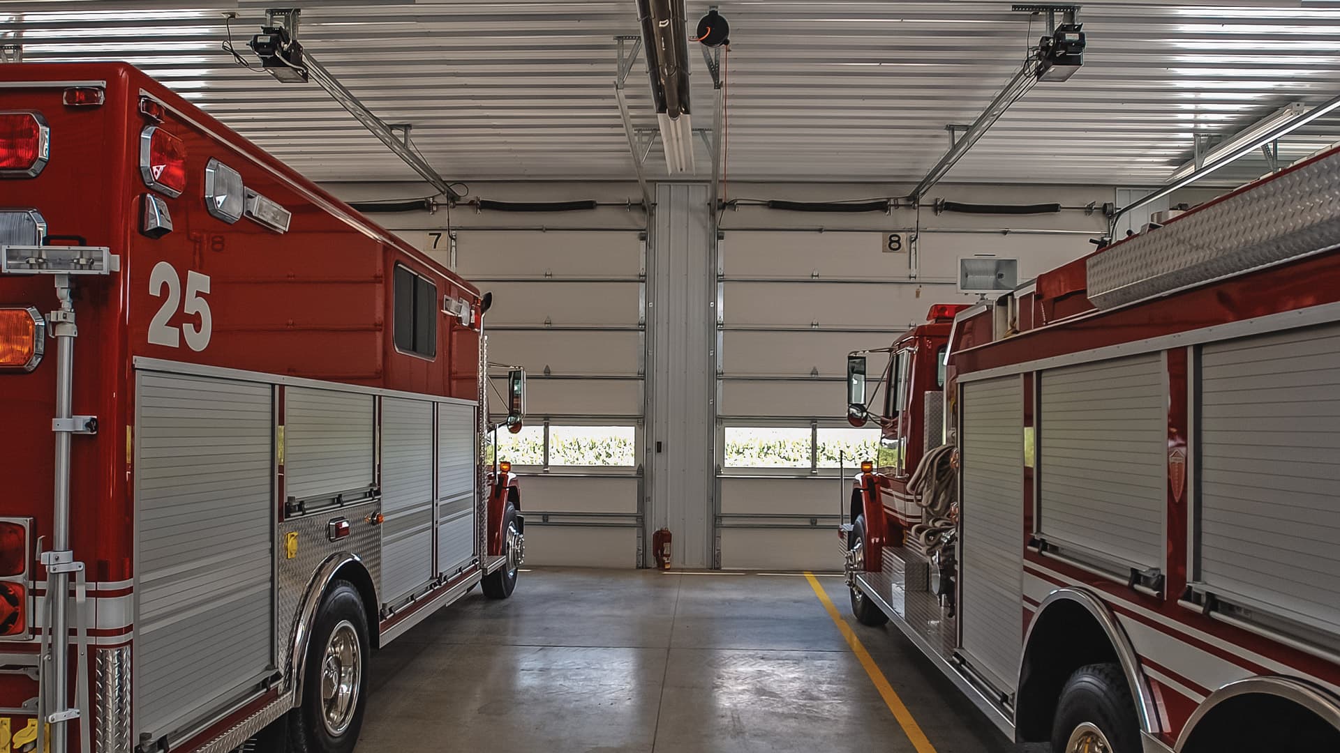 Fire truck and ambulance parked inside garage with commercial garage doors